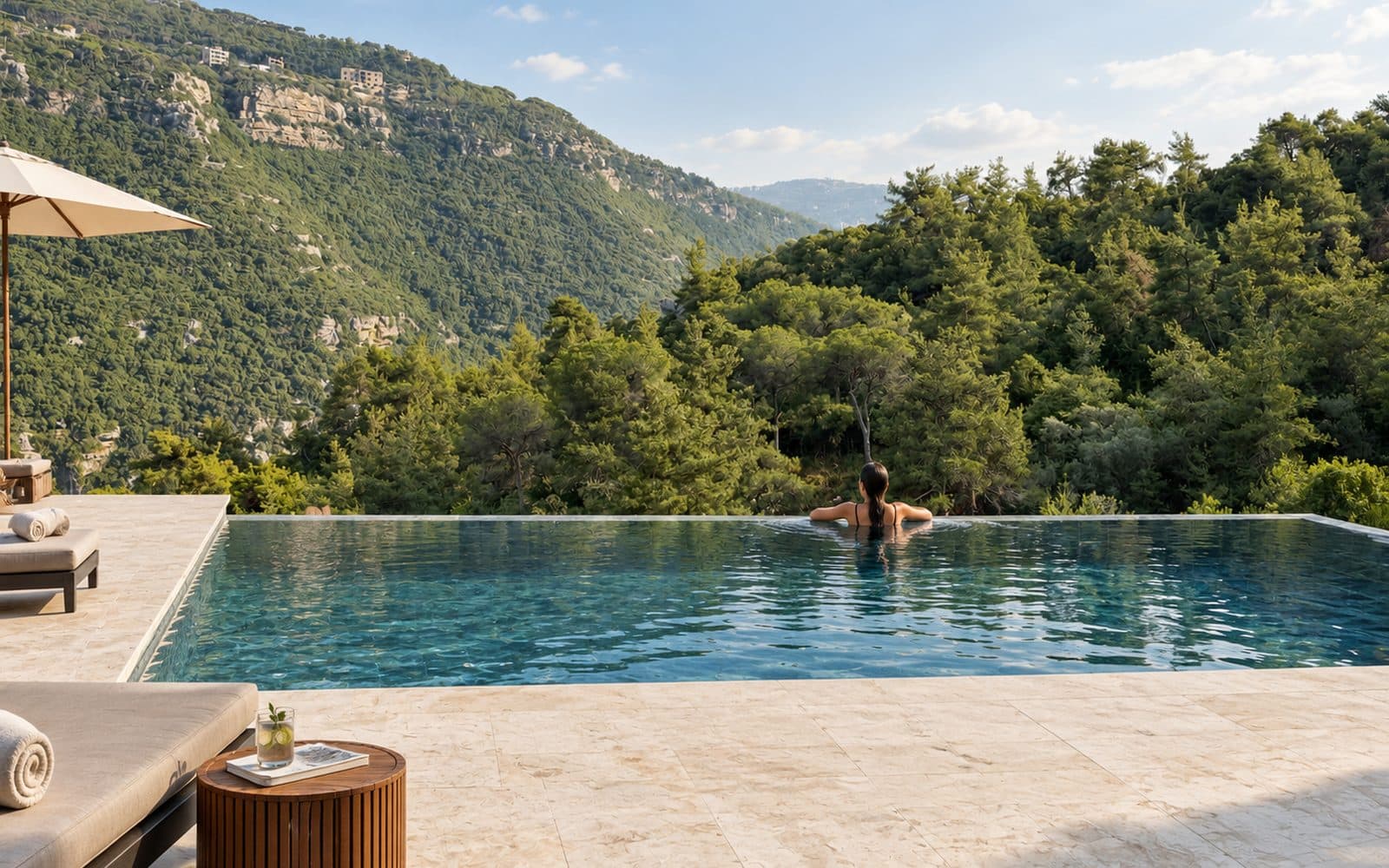 A swimmer resting at the infinity edge of the pool, facing the pine valley